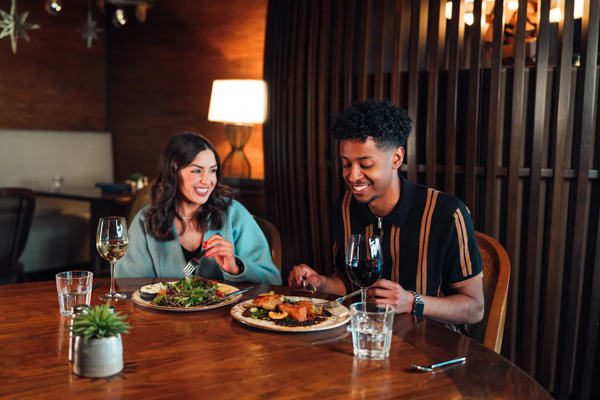 a man and woman sitting at a table eating food